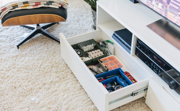 Tray Biens organizing tools and cords in the drawer of an entertainment center in a living room.